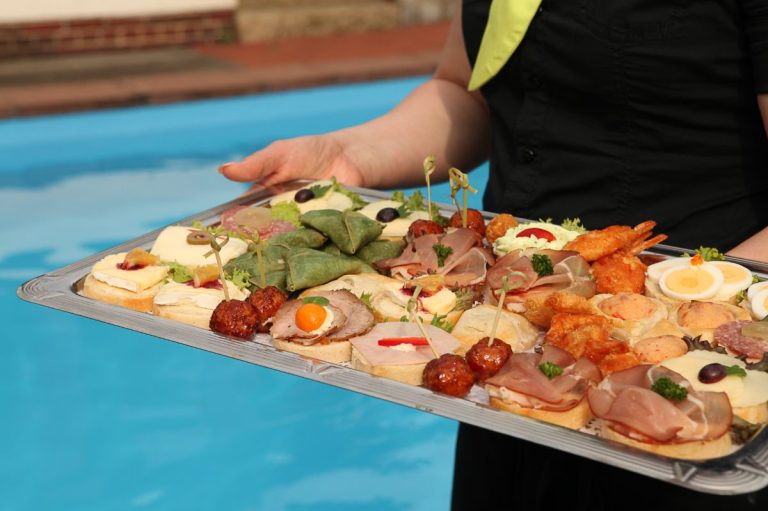 Finger-Food Hände tragen ein Tablett mit verschiedenen appetitlichen Häppchen und Finger-Food.